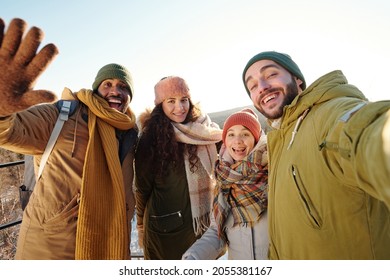 Group Of Intercultural Joyful Friends In Winterwear Making Selfie During Chill On Winter Day