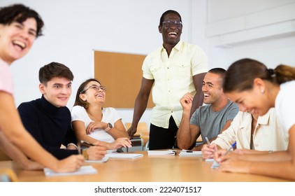 Group of interested women and men of different ages and nationalities sitting around table and communicating - Shutterstock ID 2224071517