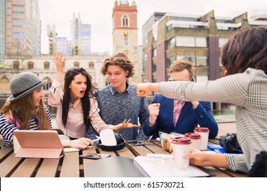 Group Of Interesting People Sit And Discuss About Something, One Of Them Speaks The Phone In Time Of A Break, Outdoors