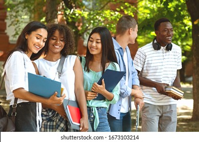 Group Of International Students Resting In Campus Outdoors During Break In Classes, Chatting And Smiling