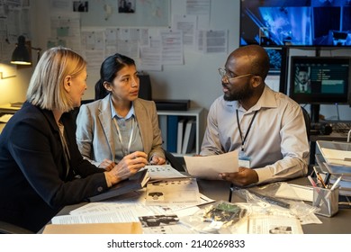 Group of interracial agents or investigators matching facts from scene of crime during discussion after questioning witnesses