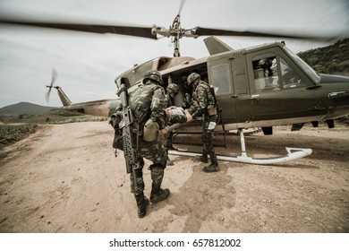 Group of Israeli elite unit combat soldiers carrying a wounded friend on a stretcher through a sandy terrain after a fierce battle against terrorists , Helicopter military medical unit