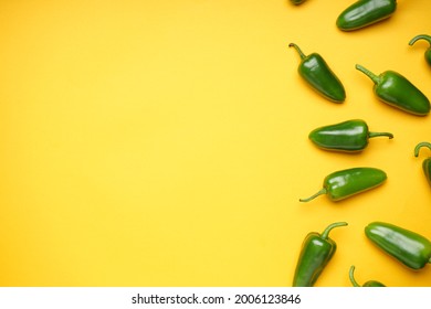 Group of jalapeno peppers on a yellow background, place for text, top view. Green chili pepper.