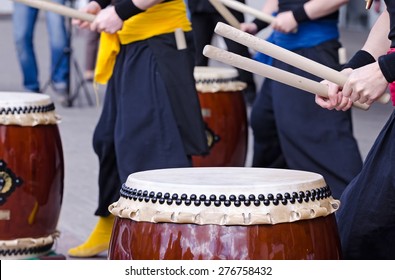 Group of japanese musicians are playing on traditional japanese percussion instrument Taiko or Wadaiko drums. The drumsticks are in the hands.