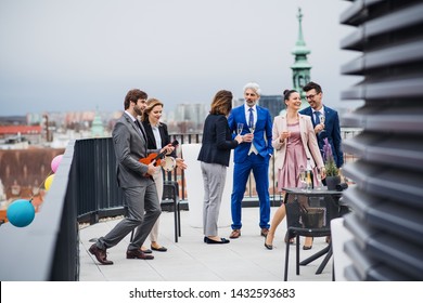 A Group Of Joyful Businesspeople Having A Party Outdoors On Roof Terrace In City.