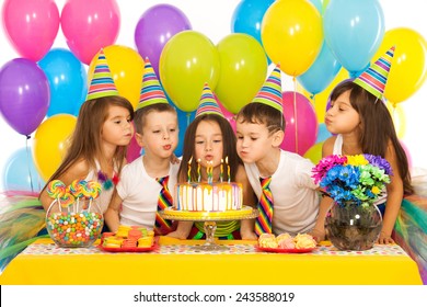 Group of joyful little kids celebrating birthday party and blowing candles on cake. Holidays concept.