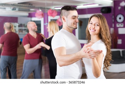 Group Of Joyful Smiling Young Adults Dancing Salsa At Dance Class. Focus On Guy