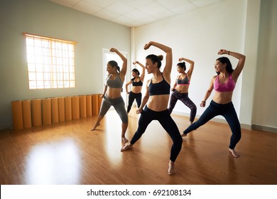 Group of joyful women wearing leggings and tops having fun while rehearsing dance in spacious studio - Powered by Shutterstock