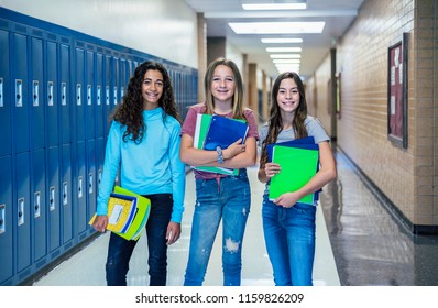 Group of Junior High school Students standing together in a school hallway. Female classmates smiling and having fun together during a break at school