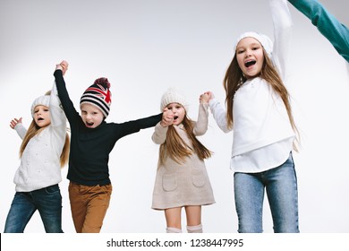 Group Of Kids In Bright Winter Clothes, Isolated On White Studio. Fashion, Childhood, Happy Emotions Concept