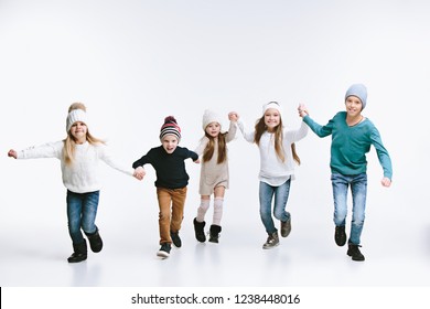 Group Of Kids In Bright Winter Clothes, Isolated On White Studio. Fashion, Childhood, Happy Emotions Concept