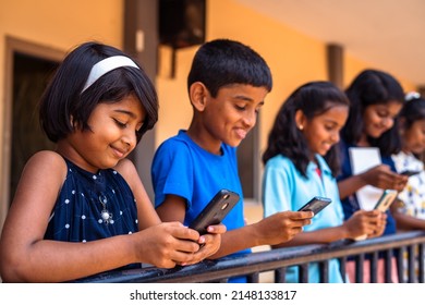 Group Of Kids Busy Using Mobile Phone At School Corridor - Concept Of Socil Media, Smartphone Technology And Gaming Addiction