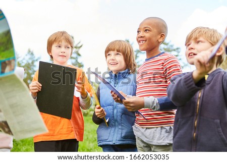 Group of kids with clipboards on scavenger hunt in nature at children's birthday party