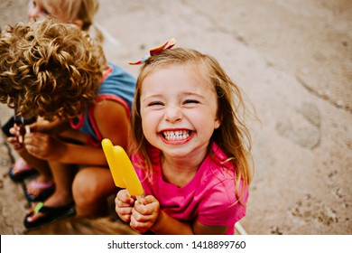 Group of Kids Eating Colorful Frozen Popsicles in the Summer