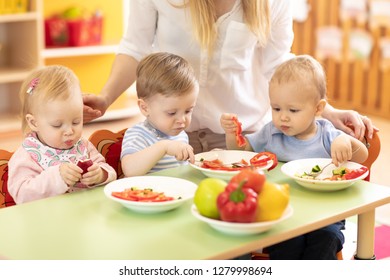 Group Of Kids Eating From Plates In Day Care Centre