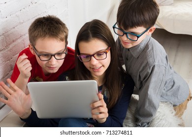 Group Of Kids In Eye Glasses Look Into Tablet. Children Computer Games, Social Networks And Media Addiction Concept. Girl And Boys With Gadget. Communication Technologies.