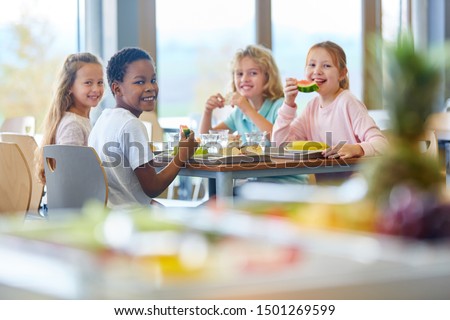 Group of kids as friends having lunch in school cafeteria