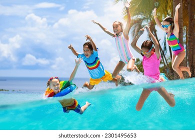 Group of kids jump into swimming pool. Summer water fun. Children play in outdoor pool. Summer family vacation with young kid. Holiday in tropical resort. Travel with child. - Powered by Shutterstock