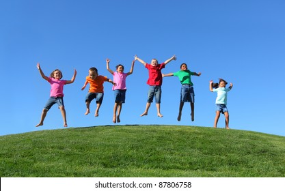Group of  kids jumping on grass hill with blue sky