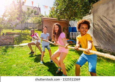 Group of kids play pulling rope game on the lawn