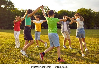 Group of kids playing games and having fun in nature. Joyful little children dancing a round dance on green grass in the park. Several happy little friends holding hands and running in a circle - Shutterstock ID 2210330083