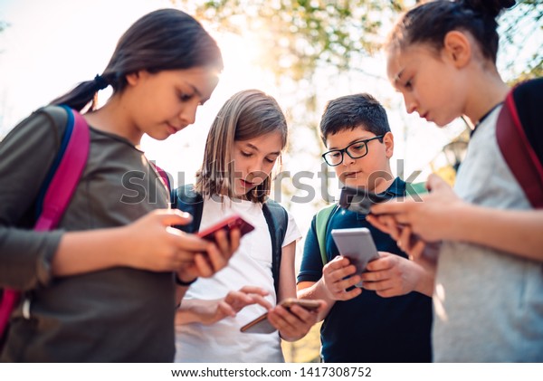 Group of kids playing video games on smart phone\
after school