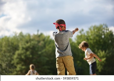 Group of kids plays blind man's buff in summer at the park