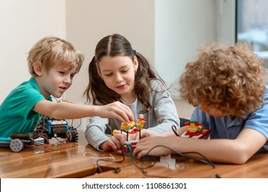 Group Of Kids Putting A Kit Together. Boys And Girl Having Fun In The Workshop. After School Activity