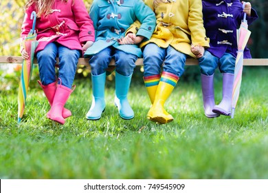 Group of kids in rain boots. Colorful footwear for children. Boys and girl in rainbow wellies and duffle coat. Rainbow foot wear and clothing for autumn or winter. Rainy weather outerwear and fashion.