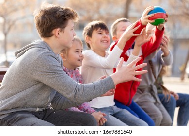 Group Of Kids Relaxing On Bench On Playground, Playing With Ball True Or False Game