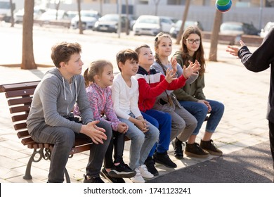 Group Of Kids Relaxing On Bench On Playground, Playing With Ball True Or False Game