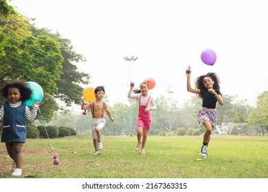 Group of kids running in the spring field at public park with balloon. Movement and blurry too soft. people children plying outdoors concept.