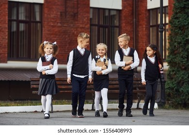 Group Of Kids In School Uniform That Is Outdoors Together Near Education Building.