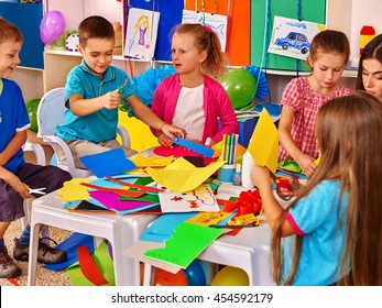 Group Kids With Techer Keeps Colored Paper On Table In Primary School . Education In Primary School.