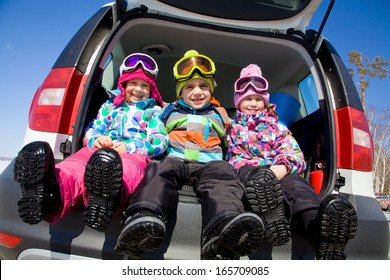 Group Of Kids In Winter Clothes Sitting In The Trunk Of A Car