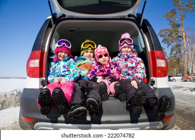 Group Of Kids In Winter Clothes Sitting In The Trunk Of A Car