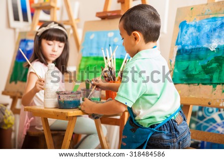 Group of kids working on a painting of a landscape during art class at school