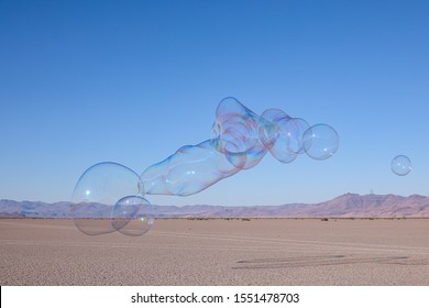 Group of large soap bubble floating above Alvord desert with Steens mountains in the background