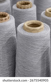 Group of large spools of thread of gray color, close up shot, abstract textile industry background
