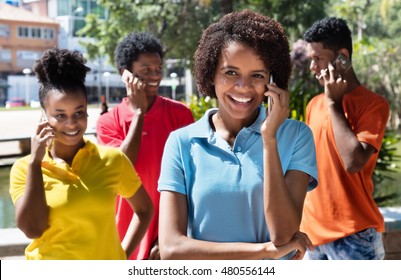 Group Of Latin American Young Adult Talking At Phone