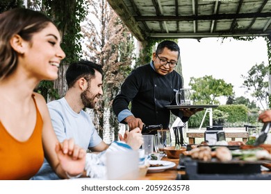 Group Of Latin Friends Eating Tacos In A Mexican Restaurant Or Bar Attended By Waiter In Mexico Latin America