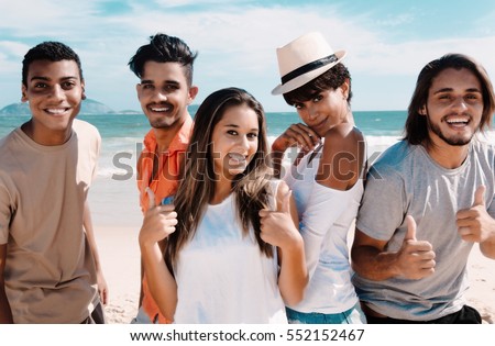 Group of laughing latin caucasian and african american men and woman at beach