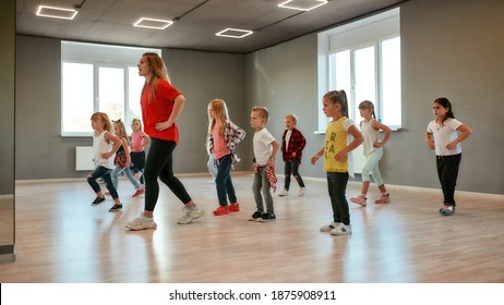 Group of little boys and girls dancing while having choreography class in the dance studio. Female dance teacher and children. Contemp dance. Hip hop. Kids and sport. Full length