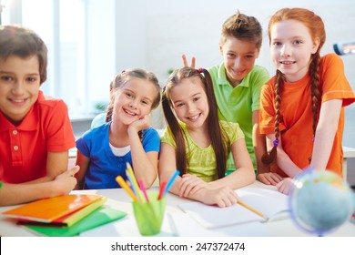 Group of little friendly schoolmates looking at camera