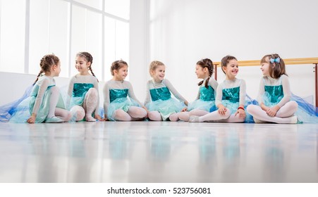 Group of a little girls in dresses taking a break from ballet class.