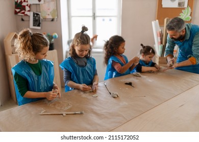 Group of little kids with teacher working with pottery clay during creative art and craft class at school. - Powered by Shutterstock