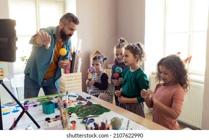 Group of little kids working on project with teacher during creative art and craft class at school. - Shutterstock ID 2107622990