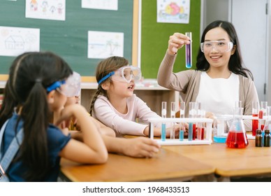 Group Of Little Pupils With Asian Female Teacher Making Experiment In Science Class. Education, Science, Chemistry And Children. Research And Development Concept.