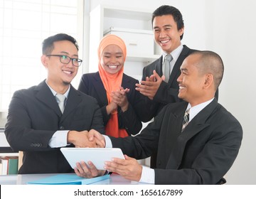 Group Of Malaysian Businesspeople Having Deals On Desk Inside Office Room, Businesspeople Clapping Hands.