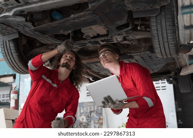 Group of male car mechanic repair automobile axle, suspension and disc brake in auto repair shop. Team of technician checking axle reduction gear underneath lift car in garage workshop - Powered by Shutterstock